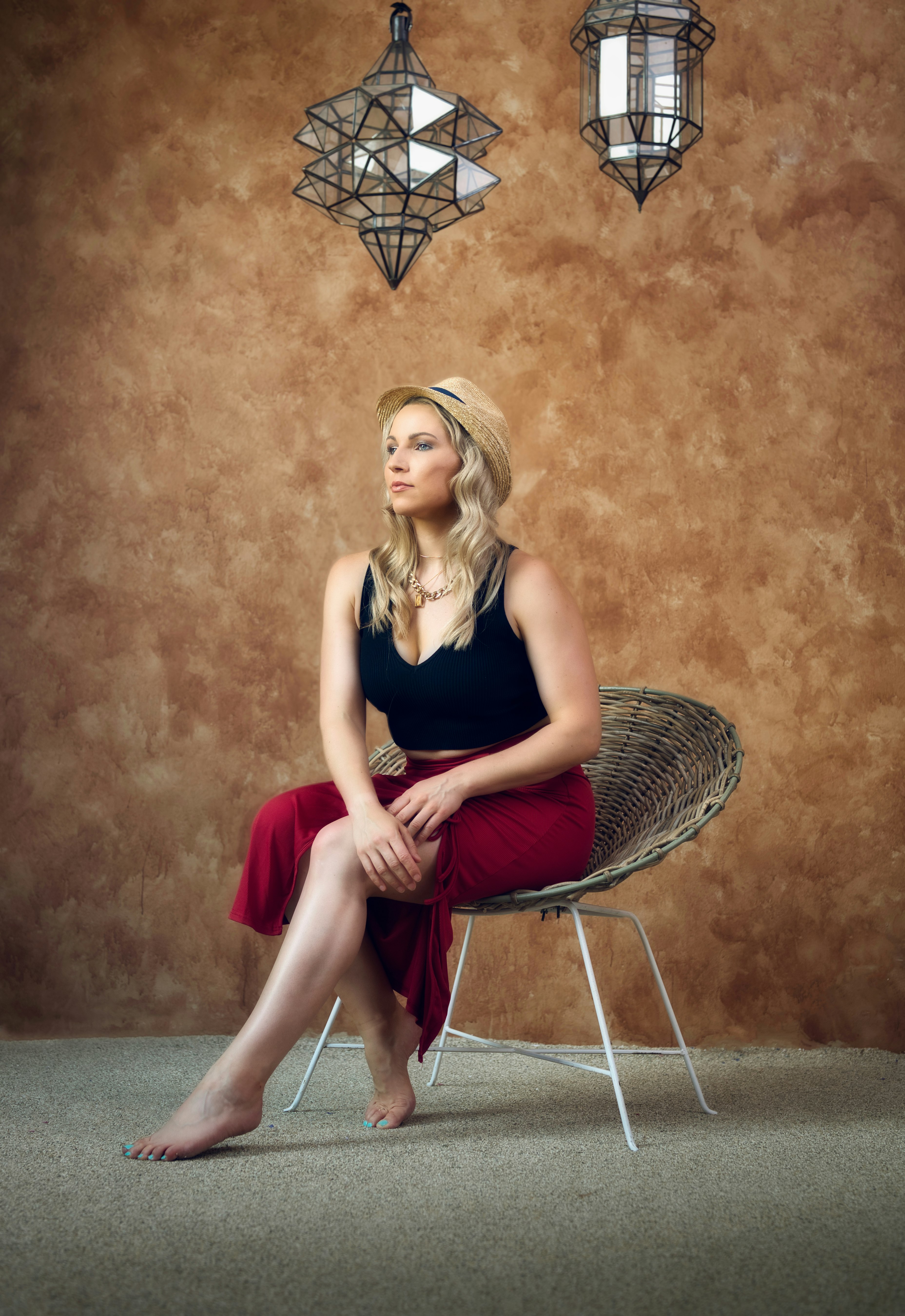 woman in black tank top and red pants sitting on brown wicker chair